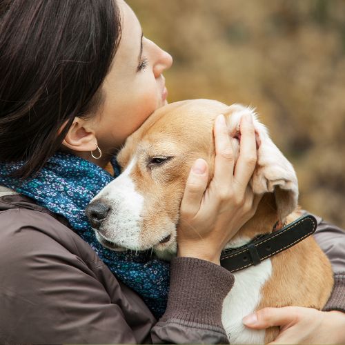hugging-dog Woman embraces a dog outdoors, conveying warmth and affection.