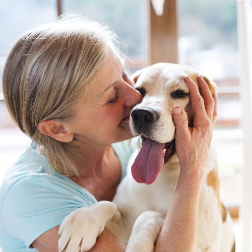 urgent-care Elderly woman affectionately hugging a dog indoors.